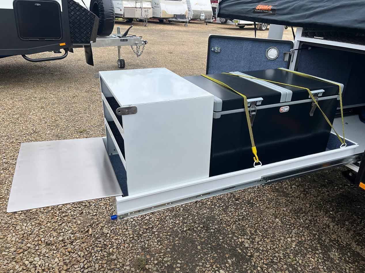 A Trailer With A Trunk Attached To It Is Parked In A Gravel Lot — Perkins Caravans in Ballina, NSW