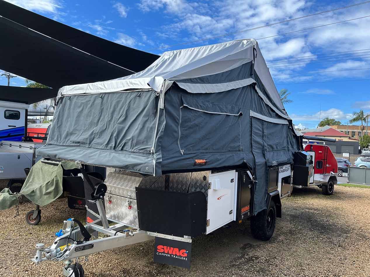 A Trailer With A Tent On Top Of It Is Parked In A Gravel Lot — Perkins Caravans in Ballina, NSW
