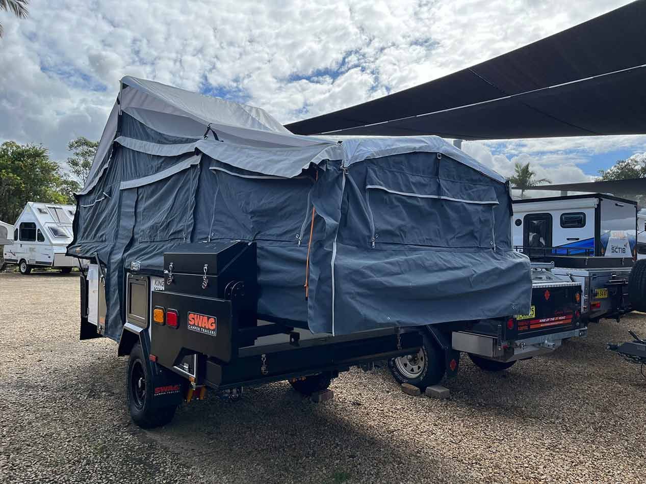 A Trailer With A Tent On Top Of It Is Parked In A Gravel Lot — Perkins Caravans in Ballina, NSW