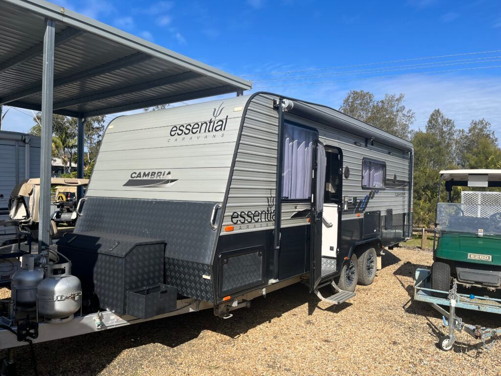 A Caravan Is Parked Under A Covered Area Next To A Golf Cart — Perkins Caravans in Ballina, NSW