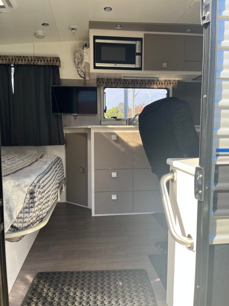 The Inside Of A Camper With A Bed And A Microwave — Perkins Caravans in Ballina, NSW