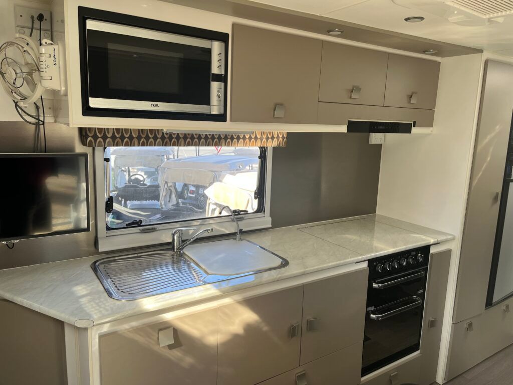 A Kitchen With A Sink, Microwave, Oven And Television — Perkins Caravans in Ballina, NSW