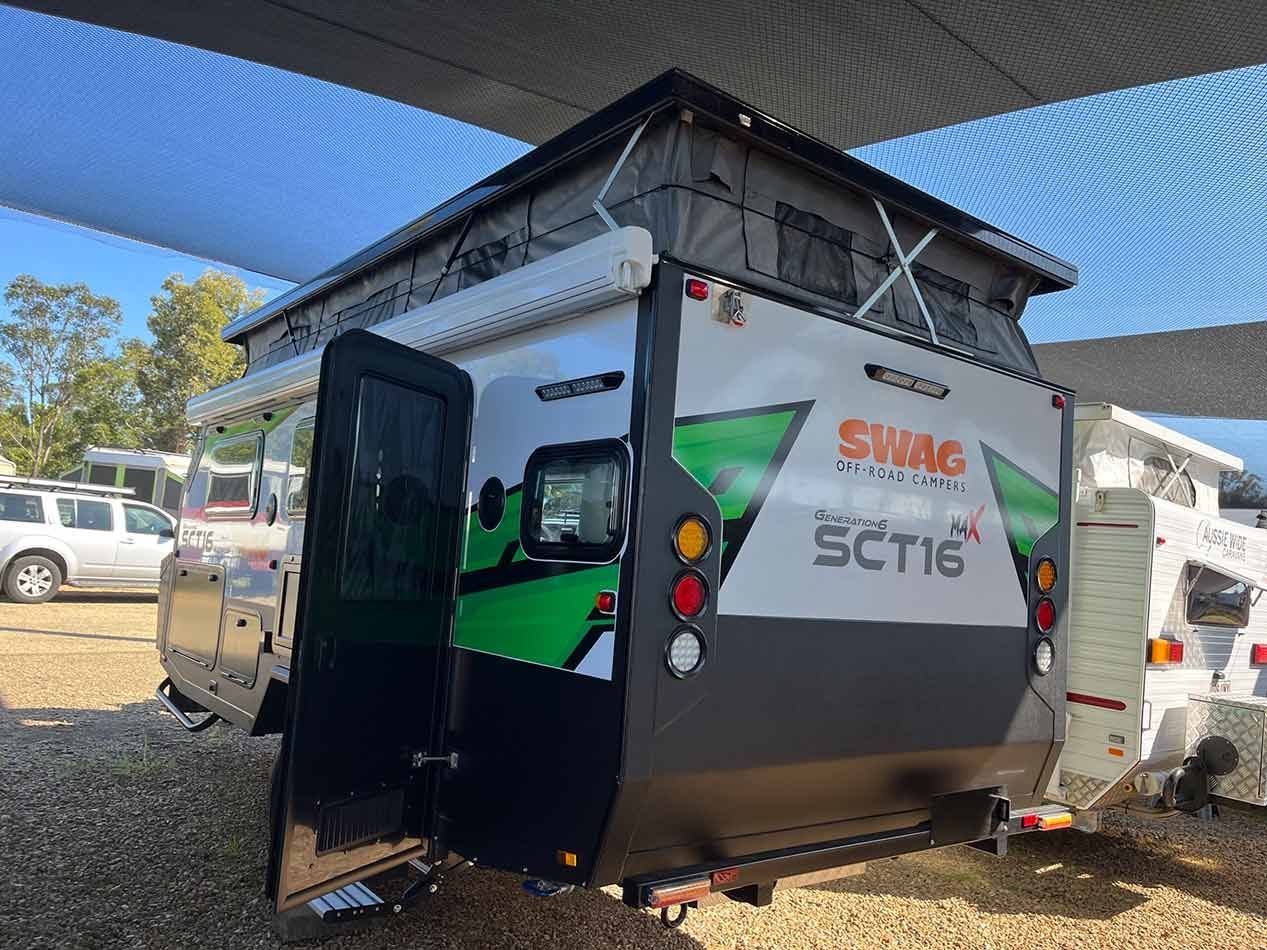 A Camper Trailer With A Pop Up Roof Is Parked In A Gravel Lot — Perkins Caravans in Yamba, NSW