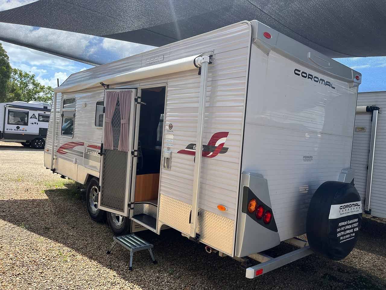 A Small White Trailer Is Parked In A Gravel Lot — Perkins Caravans in Yamba, NSW