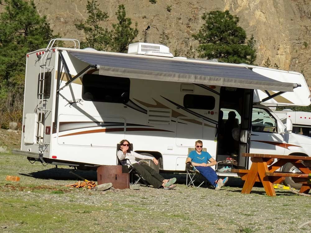 A Couple Sits In Front Of A White RV — Perkins Caravans in Lismore, NSW