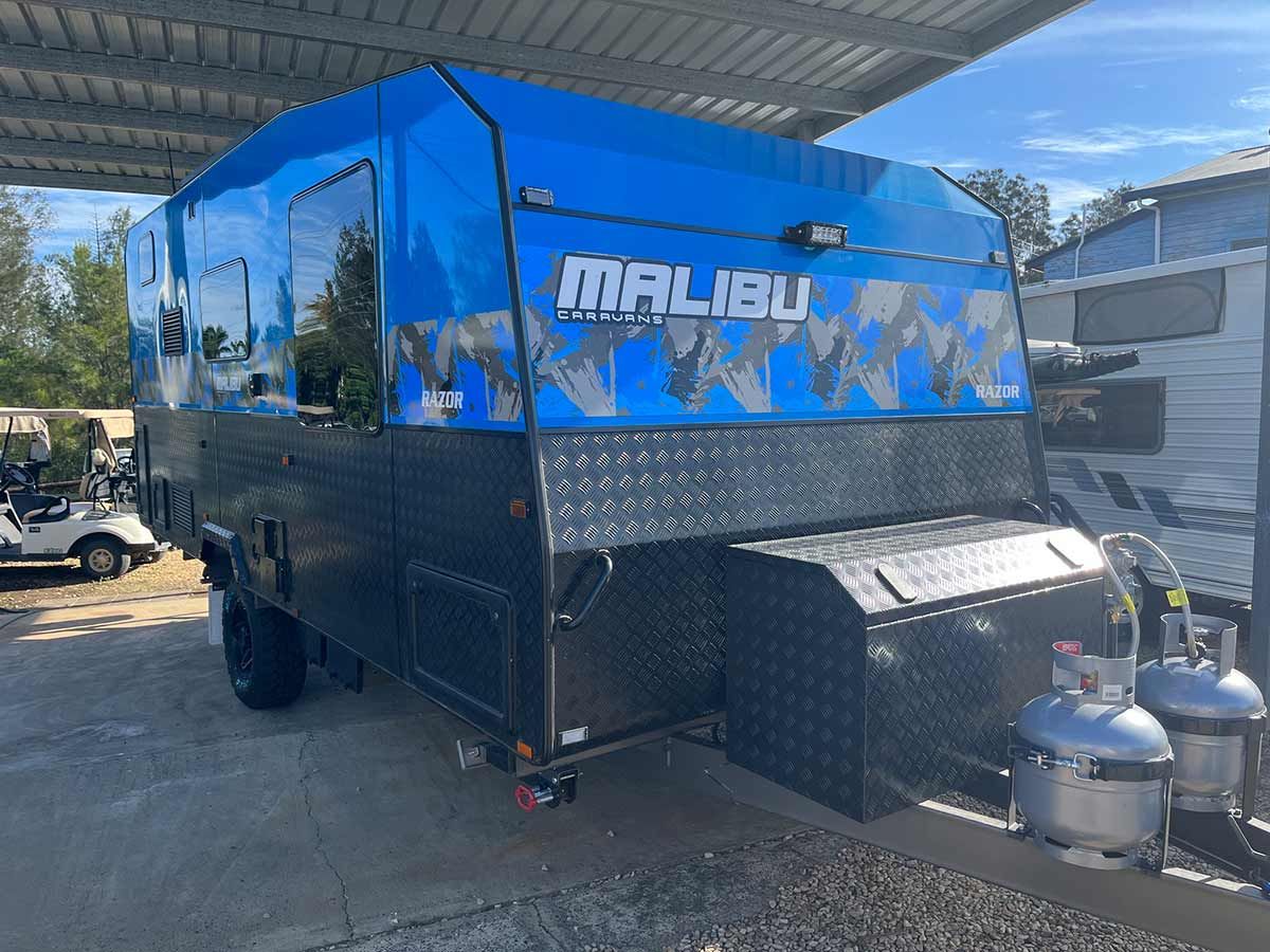 A Blue And Black Trailer Is Parked Under A Canopy In A Parking Lot — Perkins Caravans in Ballina, NSW