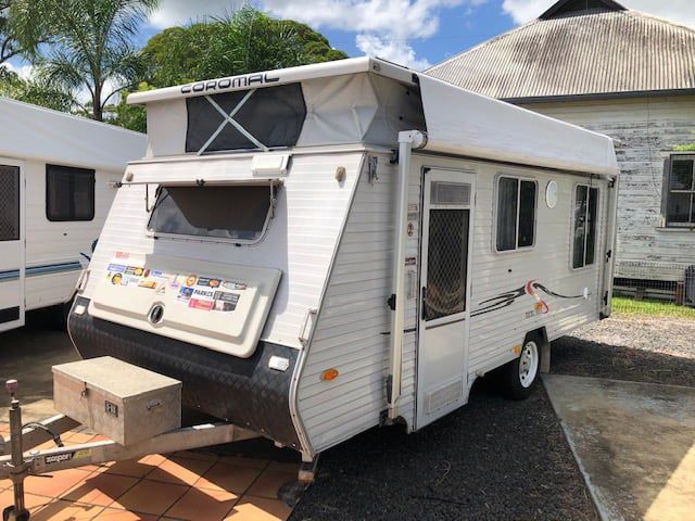 A White Trailer With A Tent On Top Of It Is Parked In Front Of A Building — Perkins Caravans in Lismore, NSW