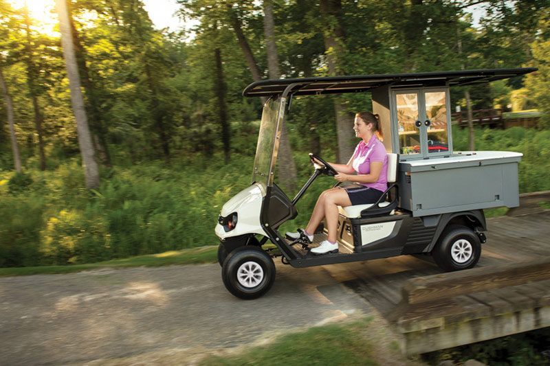 A Woman Is Driving A Golf Cart On A Path — Perkins Caravans in Ballina, NSW