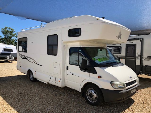A White RV Is Parked In A Gravel Lot — Perkins Caravans in Lismore, NSW