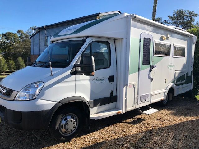 A White And Green Camper Van Is Parked In A Gravel Driveway — Perkins Caravans in Grafton, NSW