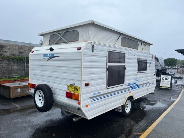 A White Trailer With A Pop Top Roof Is Parked In A Parking Lot — Perkins Caravans in Yamba, NSW