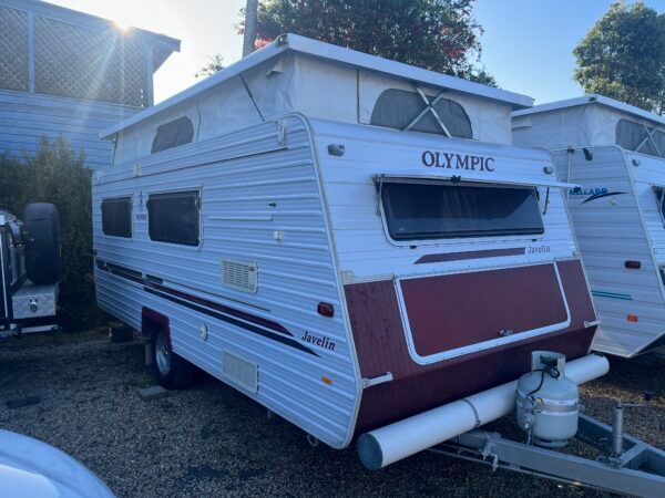 A White And Red RV With A Pop Up Roof Is Parked In A Parking Lot — Perkins Caravans in Ballina, NSW