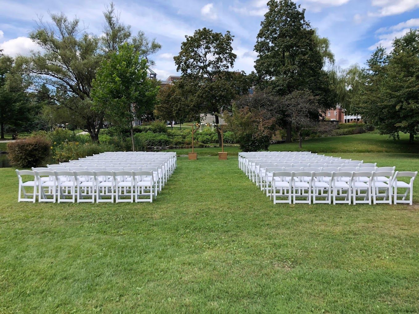 a row of white chairs are lined up in a grassy field .