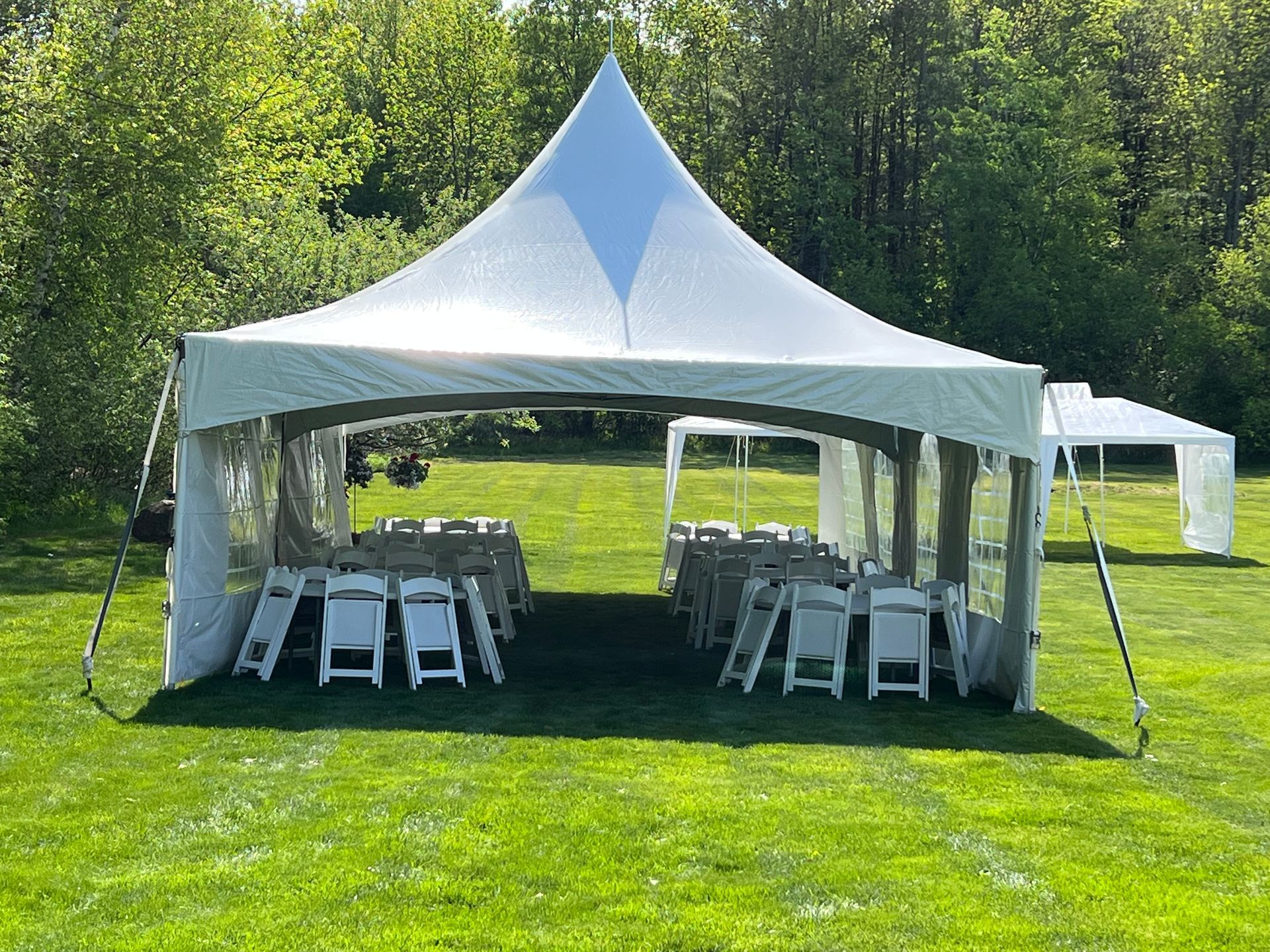 a white tent is sitting in the middle of a grassy field .