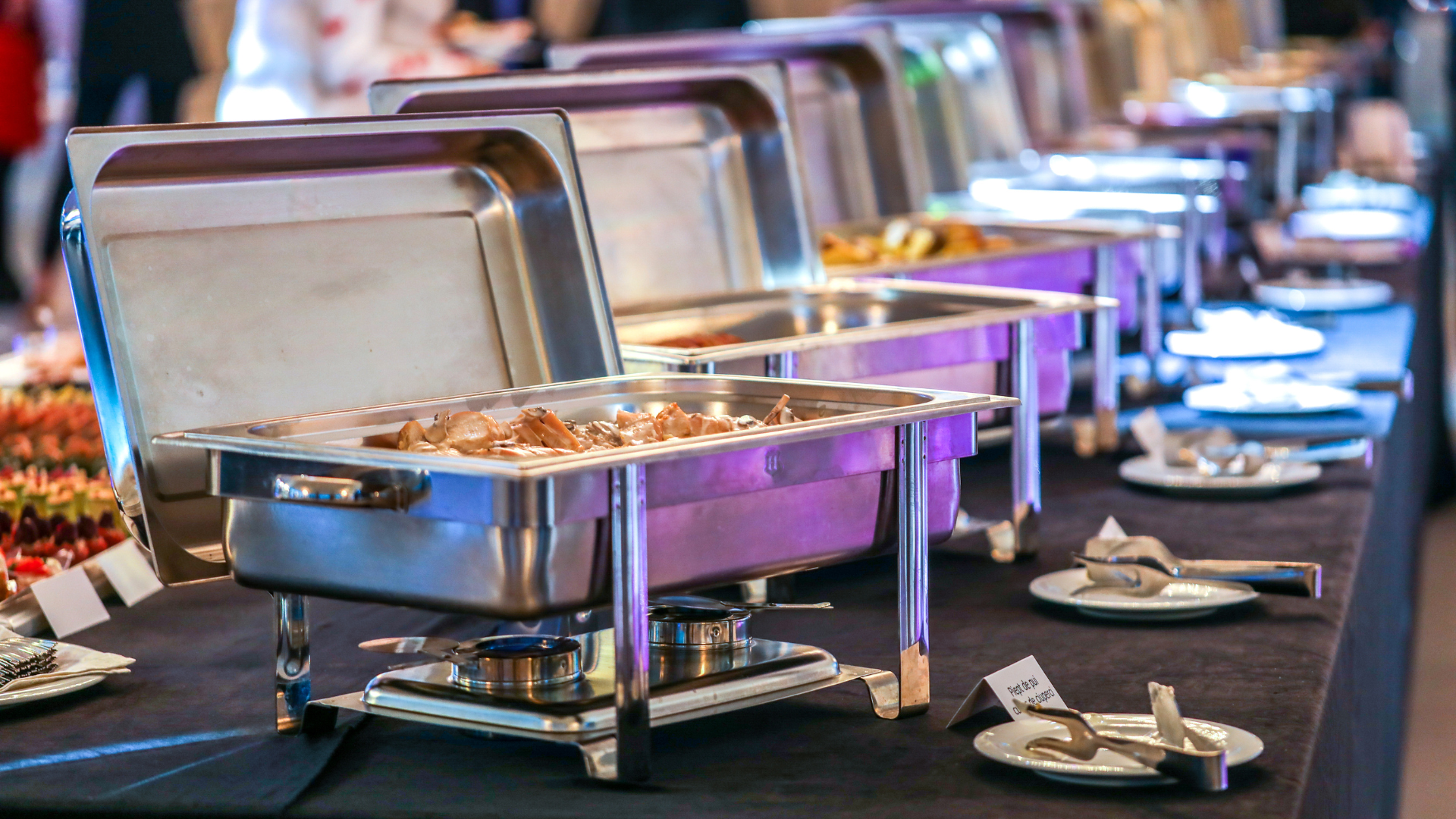 a row of buffet trays filled with food on a table .
