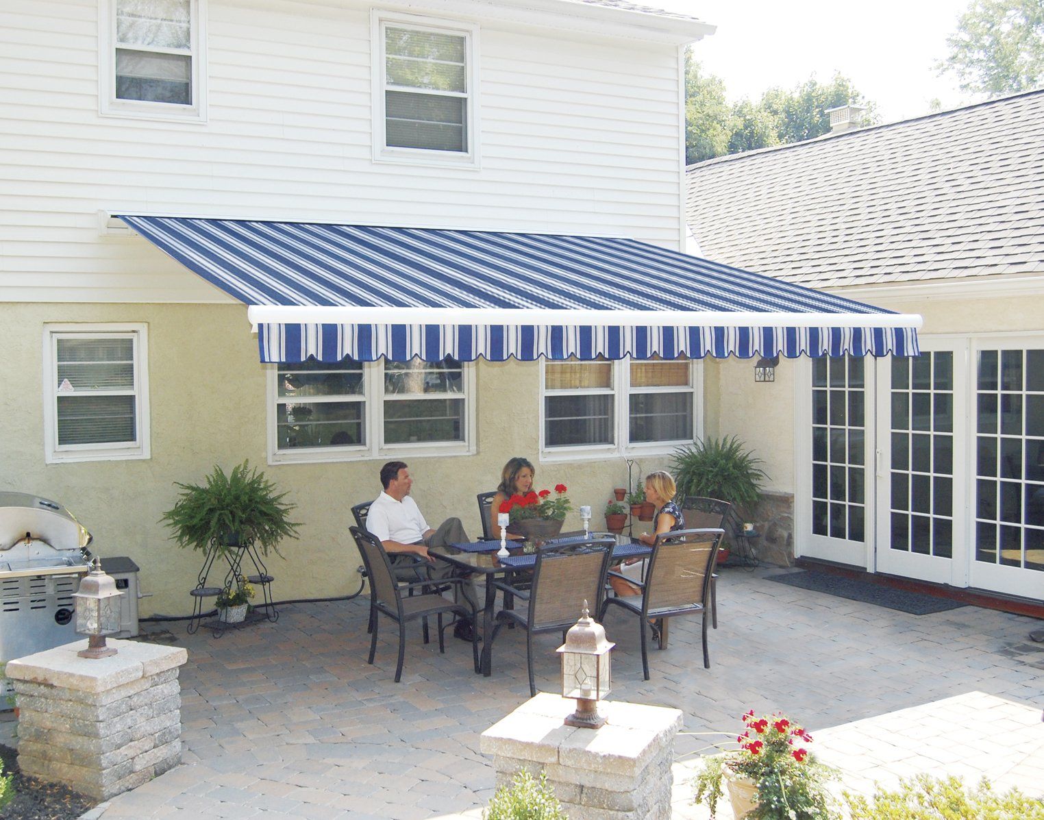 two people sit at a table under a blue and white awning