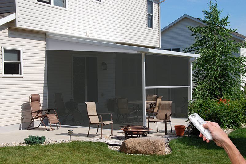 A person is holding a remote control in front of a screened in porch