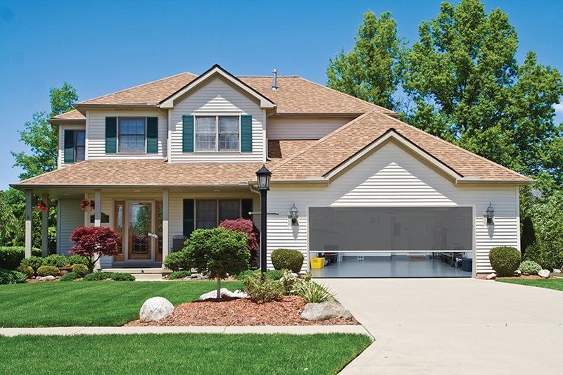 A white house with a brown roof and a gray garage door