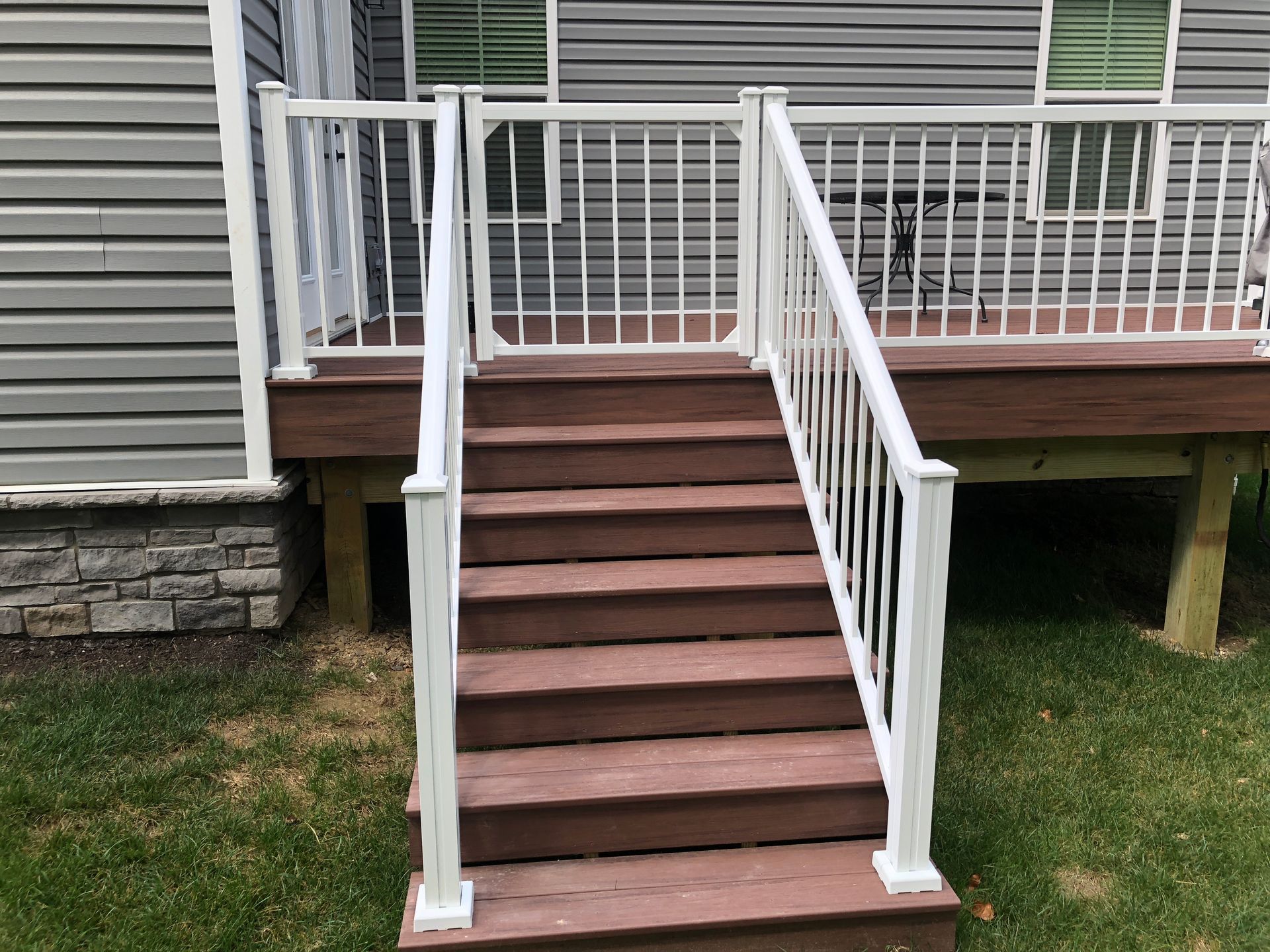 A deck with stairs leading up to it and a white railing