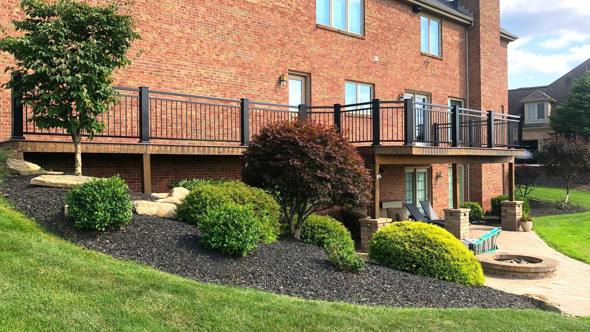 A brick house with a deck and a patio in front of it.