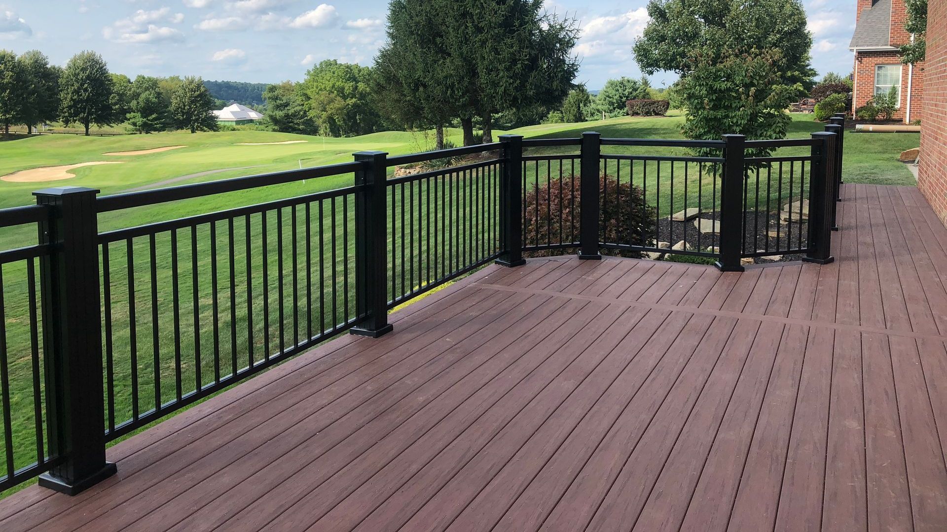 A deck with a black railing overlooking a golf course