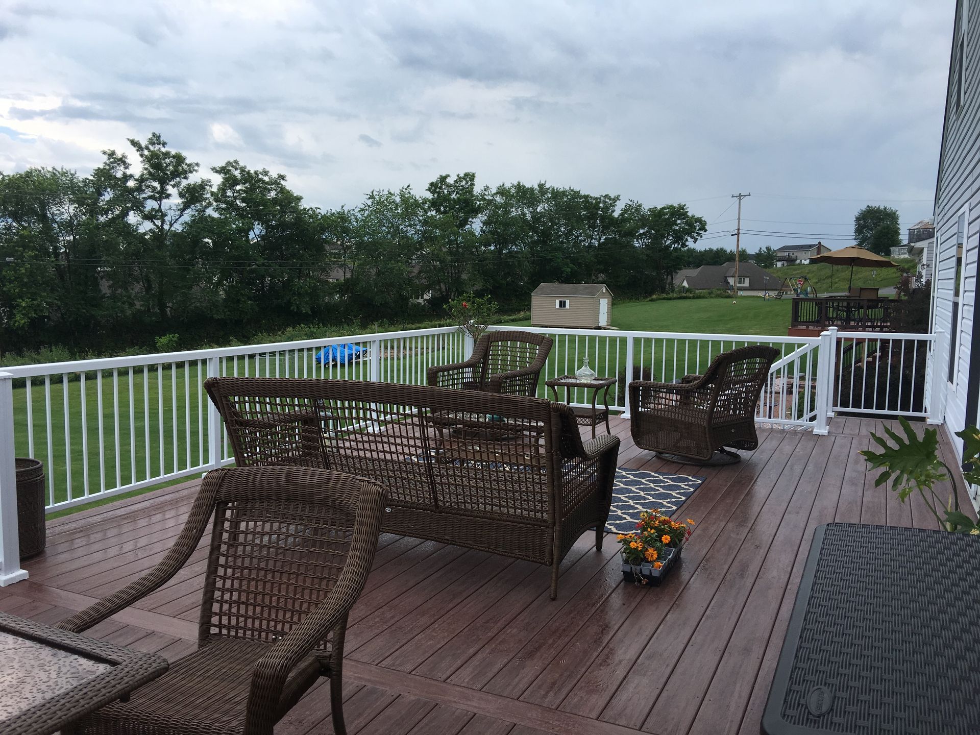 A deck with wicker furniture and a white railing