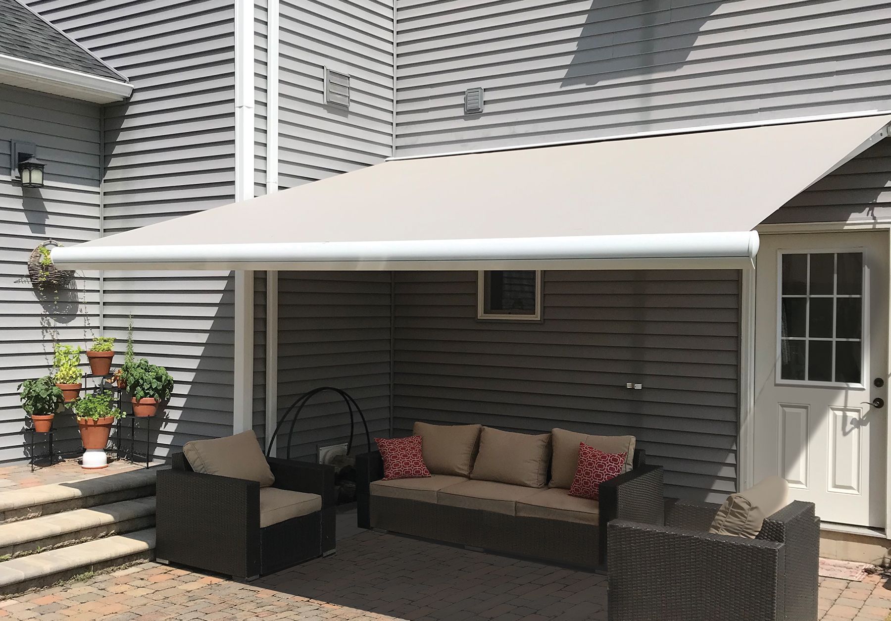 A patio with a couch and chairs under an awning