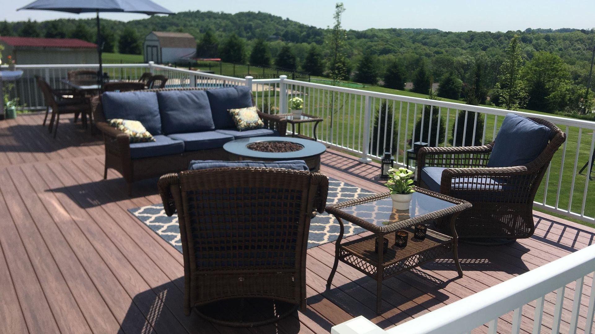 A deck with a couch and chairs and an umbrella