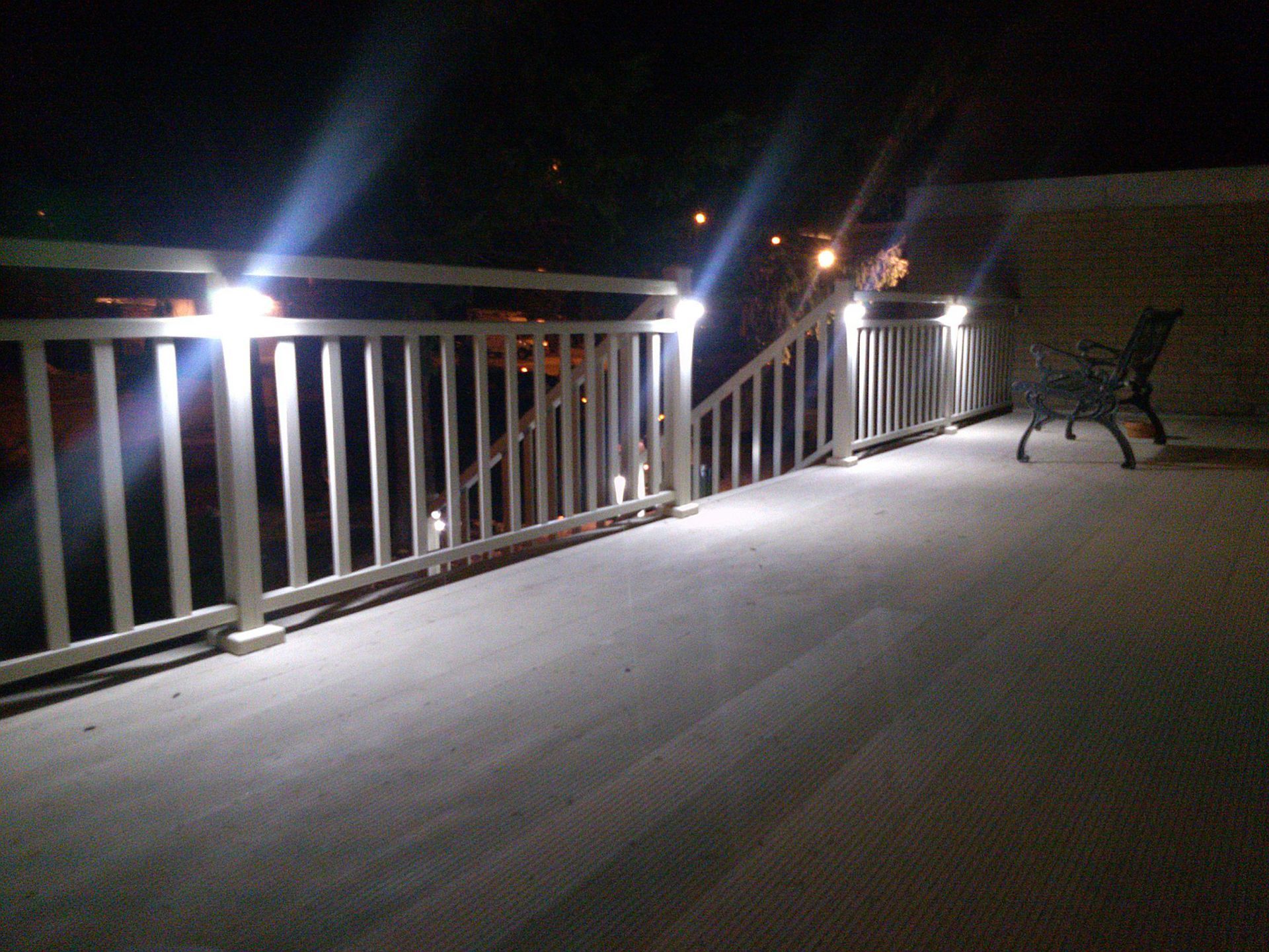A railing with lights on it is lit up at night by Premier Decks & Awnings
