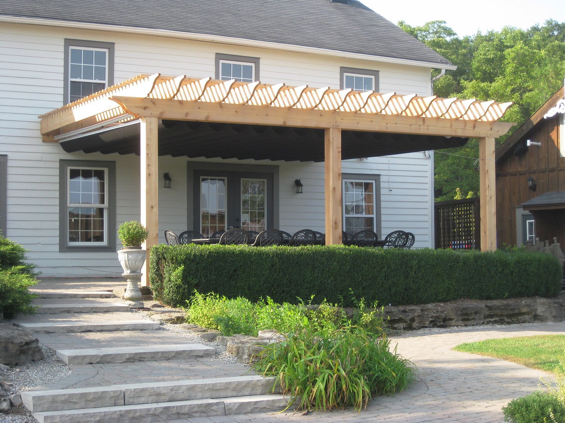 A white house with a wooden pergola on the front porch