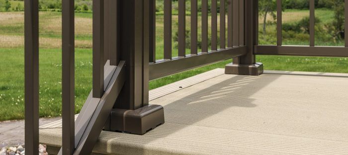 A close up of a railing on a deck with a grassy field in the background  by Premier Decks & Awnings