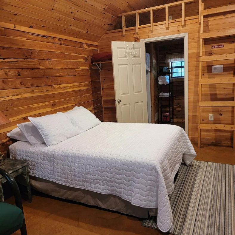 Cozy log-cabin bedroom with a neatly made white bed and wooden walls