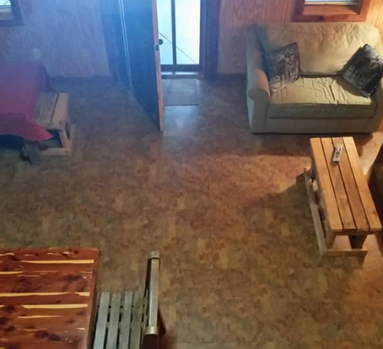 A cozy living room with a sofa, wooden bench, chairs, and a table on a tiled floor.