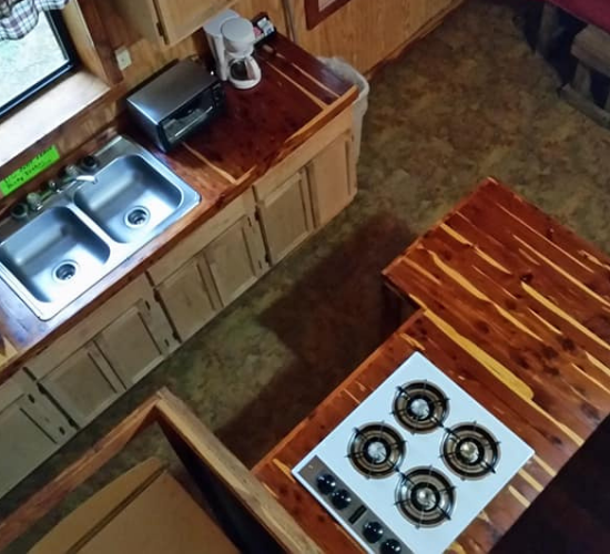 Small kitchen with wooden counters, a double sink, and a white gas stove viewed from above.