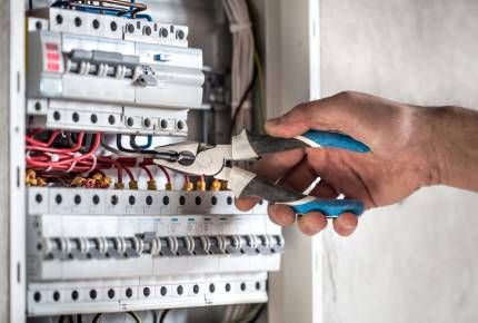 A man is fixing a light switch with a screwdriver.