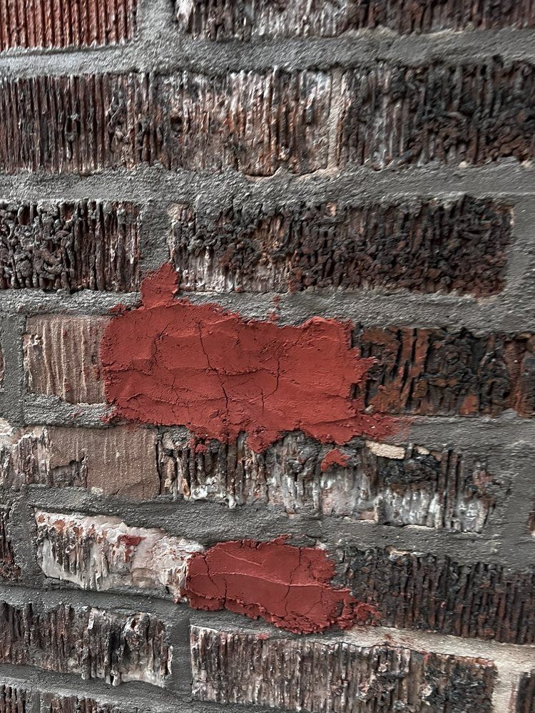 Brick wall with red patches of filler.