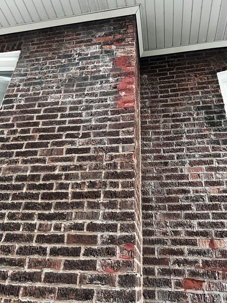 Brick exterior wall with white efflorescence and a white soffit.