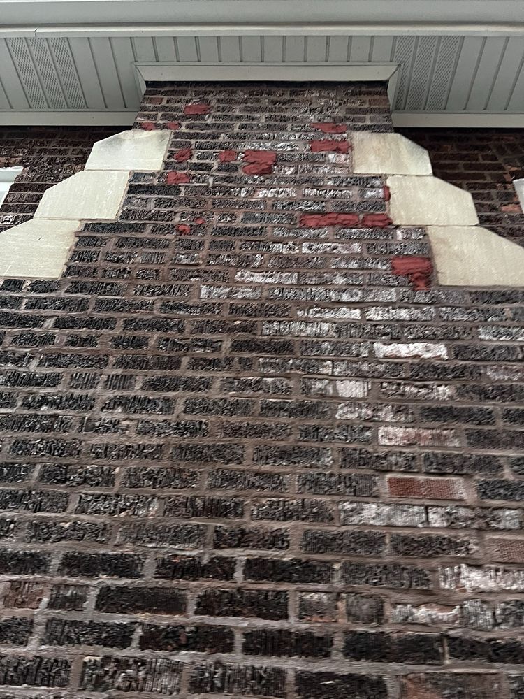 Brick chimney with red and white bricks and decorative light-colored stone accents.