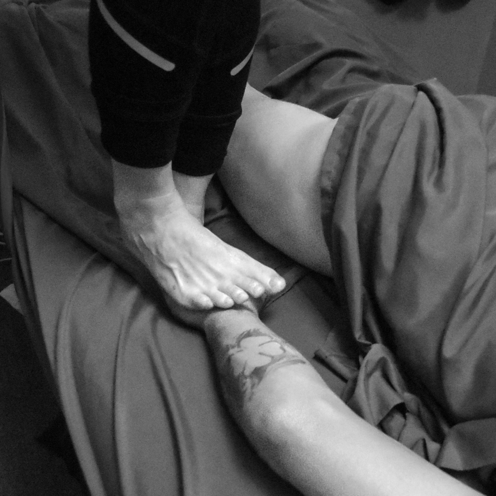 Black and white image of barefoot neck massage, highlighting the calming and therapeutic experience at The Traveling Sole