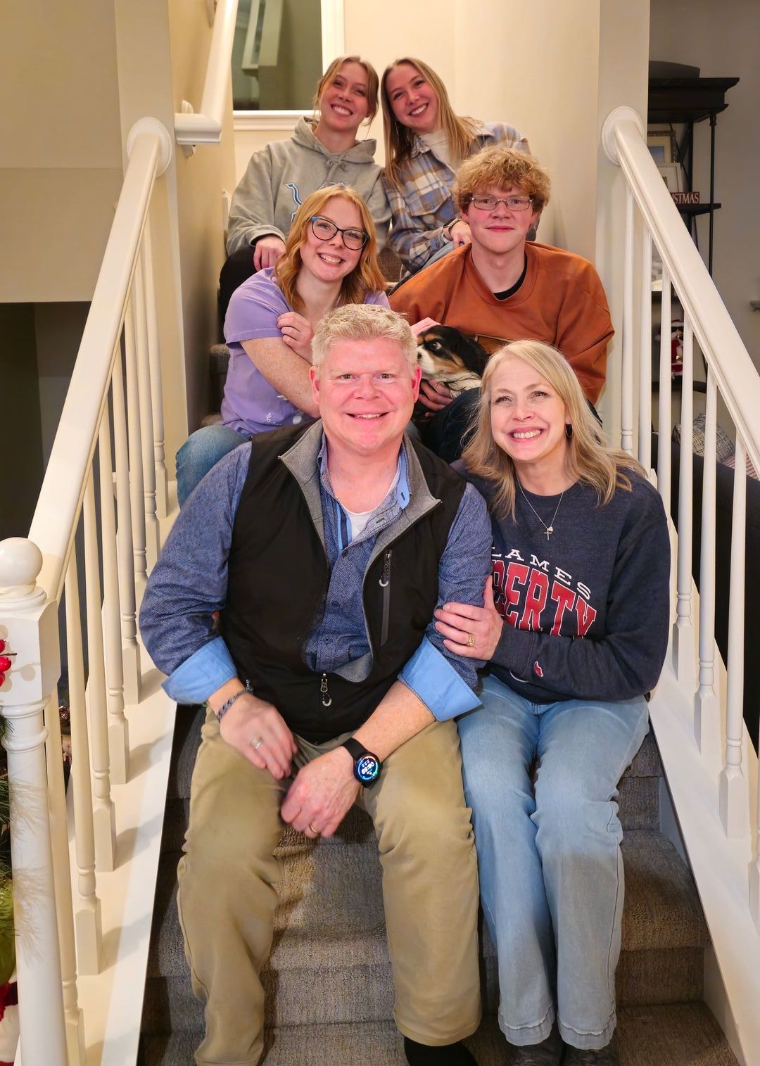 Adam Stewart and his family are posing for a picture on a staircase at home.