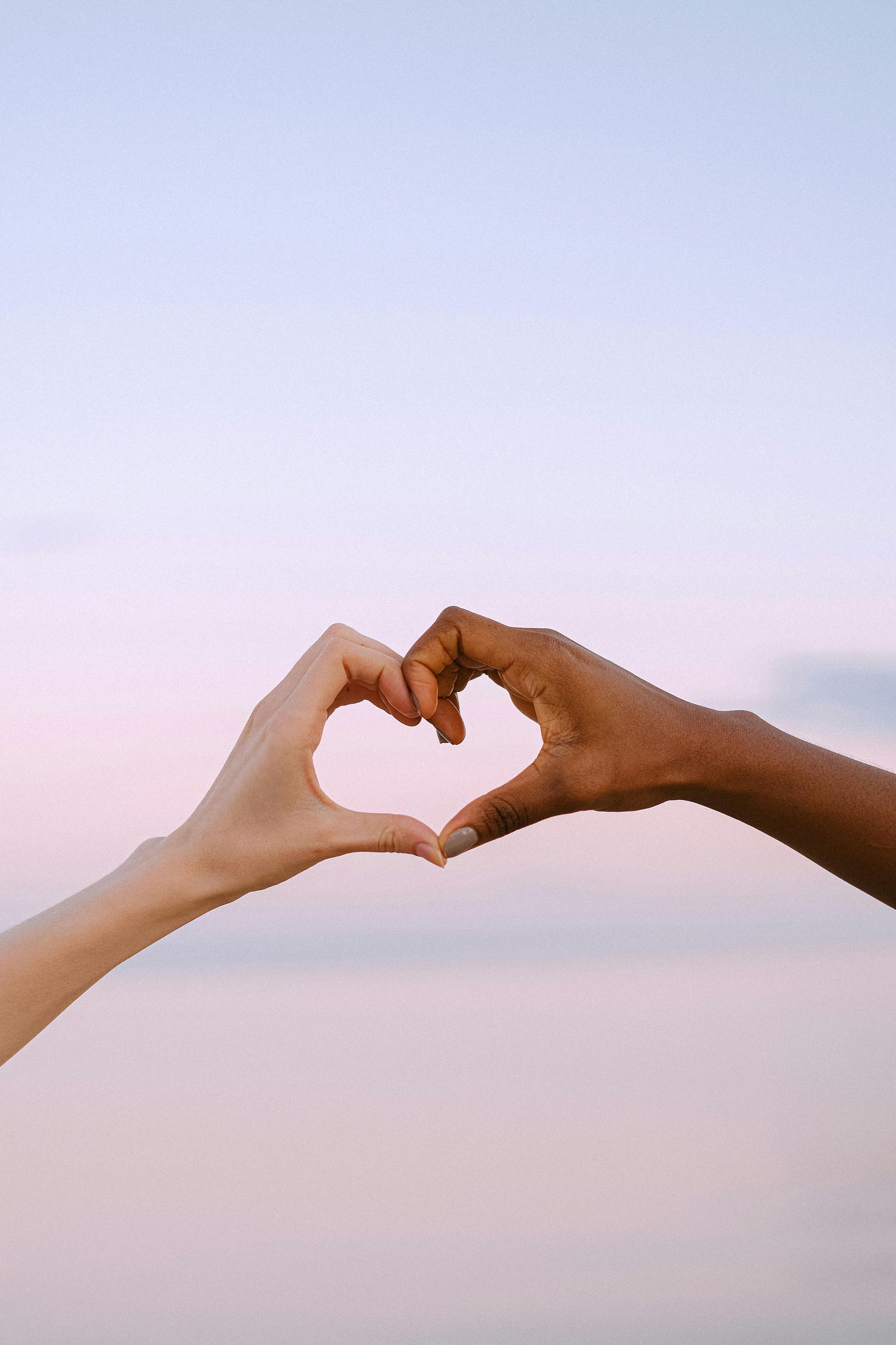 Two people are making a heart shape with their hands.