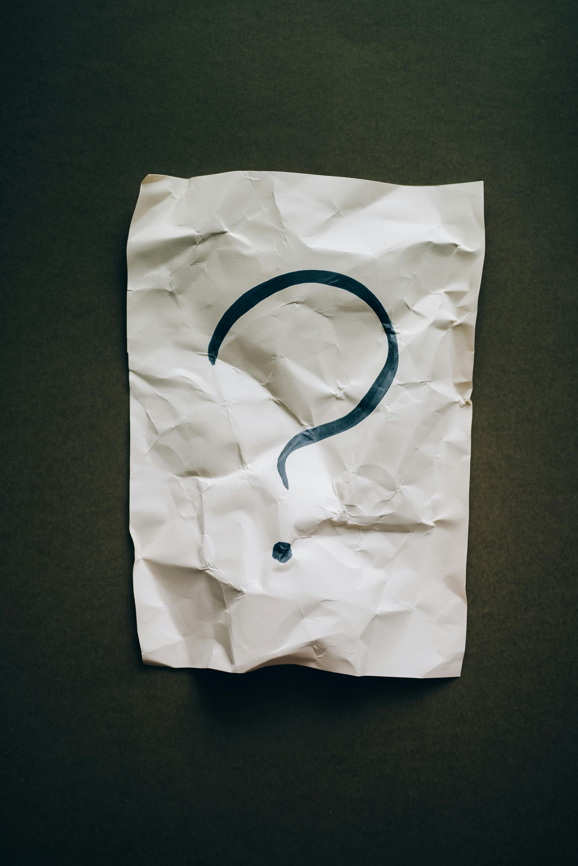 A piece of crumpled paper with a question mark drawn on it.