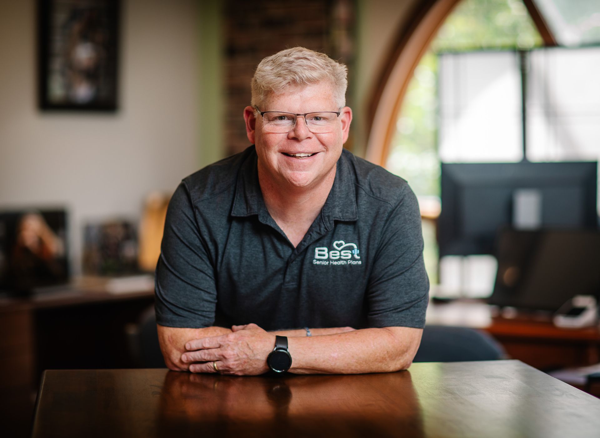 Founder Adam Stewart is sitting at a table with his arms crossed and smiling.