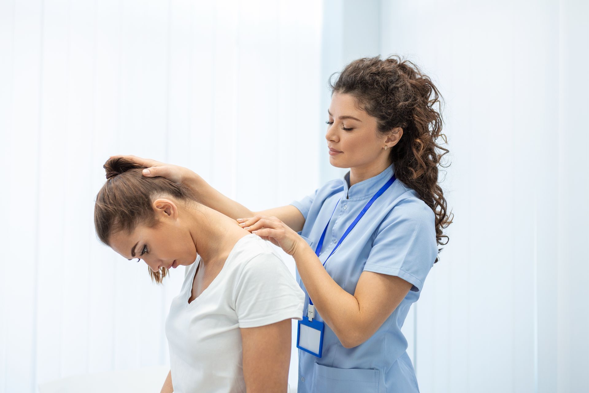 A nurse is examining a patient 's neck in a hospital.