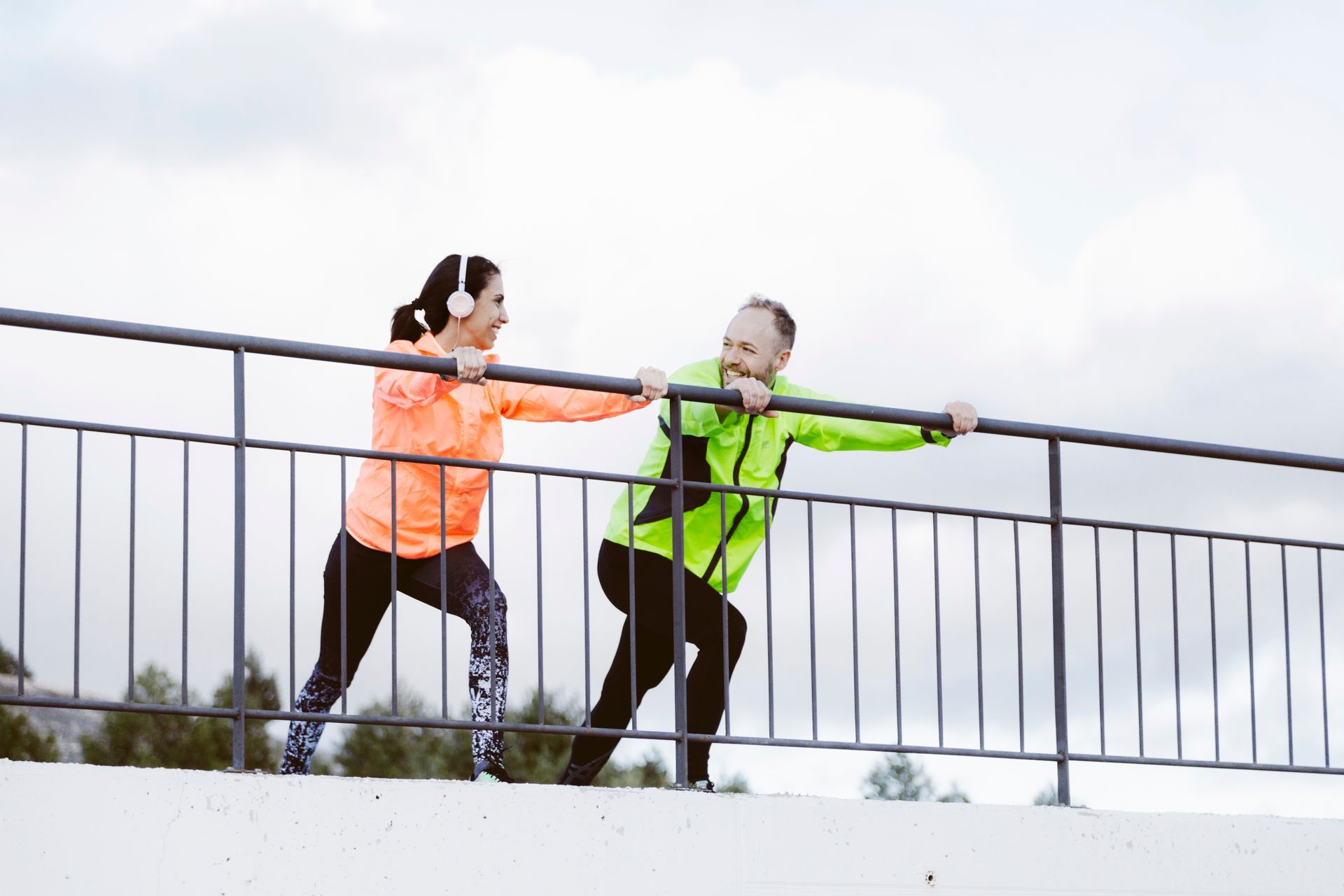 A man and a woman are holding onto a railing on a bridge.