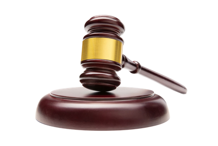 Judge’s gavel resting on a round wooden base against a white background