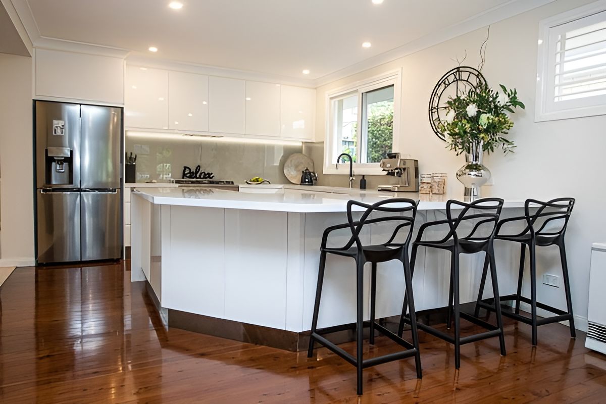 A Kitchen With a Large Island , Stools , a Refrigerator and a Clock on the Wall — Stephen Veigel Kitchens In Erina, NSW