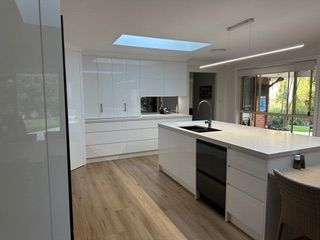 Modern white kitchen with island, wooden floors, and skylight - Stephen Veigel Kitchens In Gosford, NSW