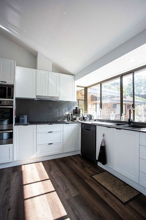 A Kitchen With White Cabinets , a Black Dishwasher , and a Large Window — Stephen Veigel Kitchens In Gosford, NSW