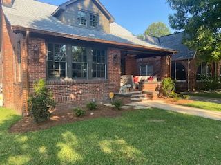 A Brick House With a Porch and a Large Lawn in Front of It
